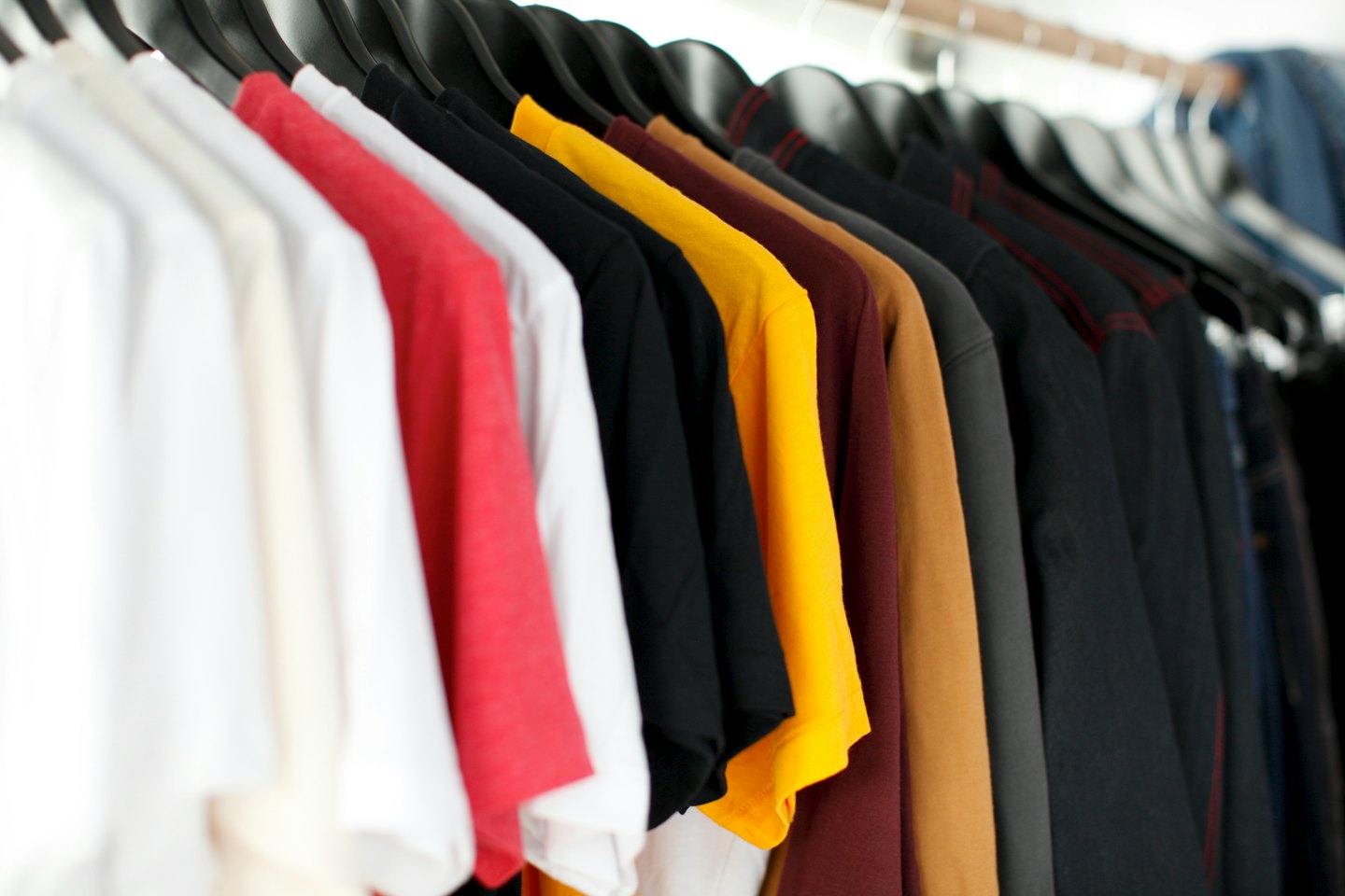 Camisetas de manga corta y larga de colores colgadas en perchas.